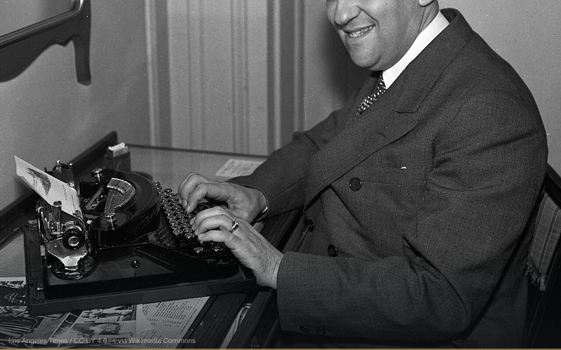 Dr. Morris Fishbein sitting at his typewriter, most likely at the Biltmore Hotel, where he stayed with his wife, while on a brief tour stopping in Los Angeles. He prepares an article for the Journal of the American Medical Association. — related to Alternative Medicine Suppression